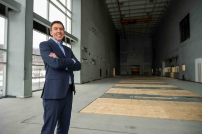 Paul Malliband stands in industrial space formerly a printing facility, now hollow with high ceilings will be used for battery prototyping in the future.