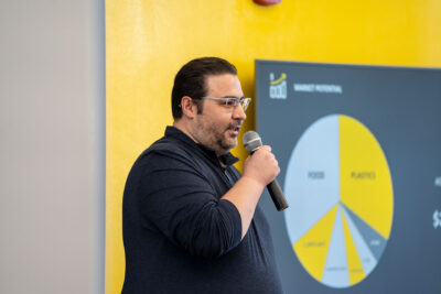 Man holds microphone presenting innovation from MITO Materials during ChargeUp final pitch showcase. 